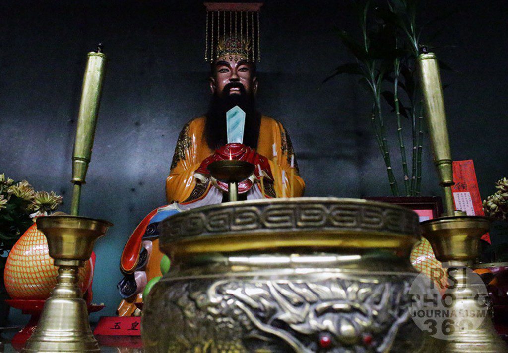 A monument of The Jade Emperor in front of a burning candle at the Fung Loy Kok Institute of Taoism in downtown Toronto. The candle burns constantly to purify the surroundings. This photograph was taken on Nov, 5 2015