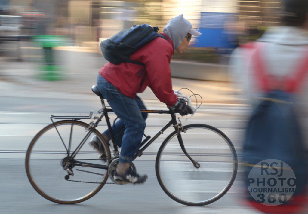 A man riding a bicycle speeds by Ryerson University students on Church and Gould Streets, on Monday, November 9th 2015.  Photo by Ebyan Abdigir